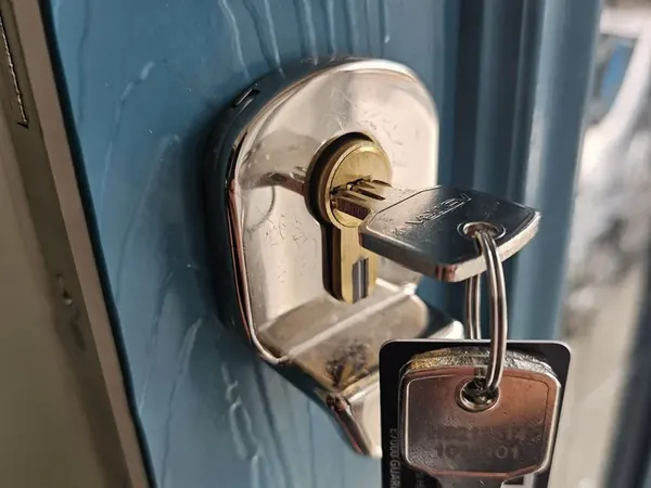 Euro cylinder with security escutcheon and keys on a blue door