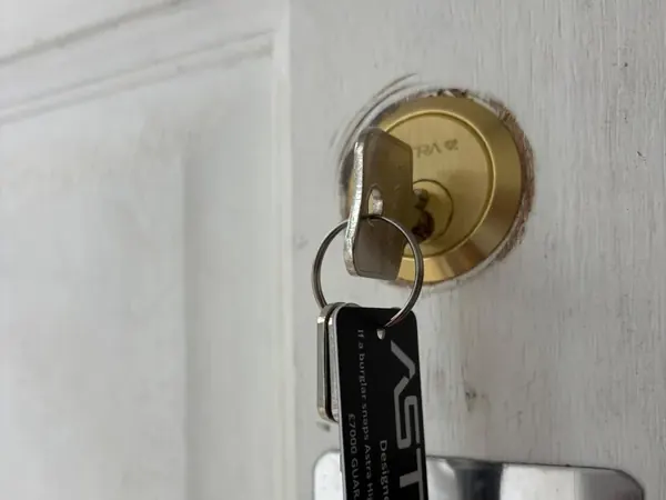 New brass rim cylinder with keys and key tag on a white door