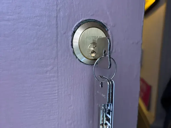 Rim cylinder with new keys on a lilac painted door