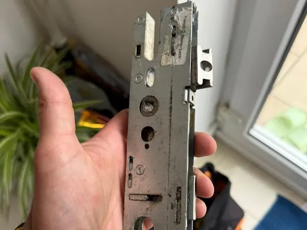 Worn uPVC multipoint gearbox held in the hand after removal