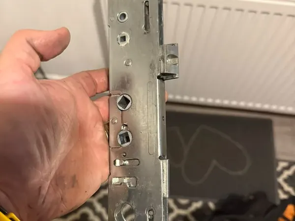 Locksmith holding a multipoint lock gearbox before fitting